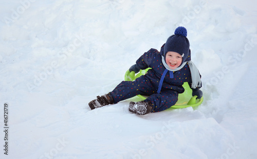 A little boy is riding a slide. Winter.