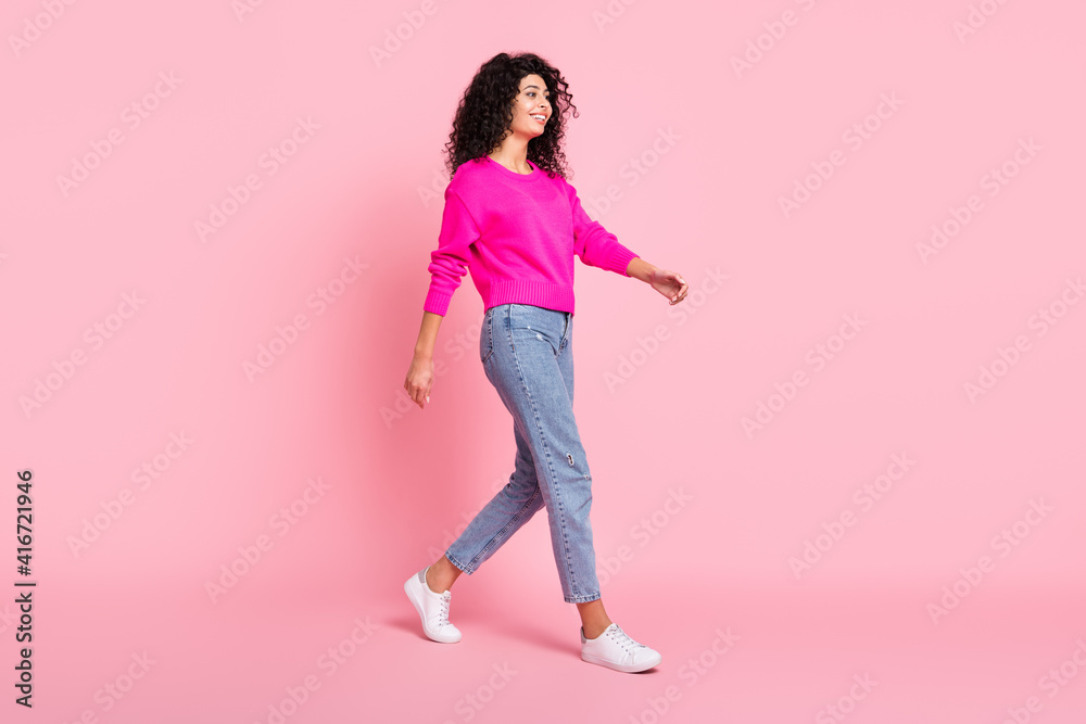 Full size profile side photo of young cheerful smiling lovely pretty go walk step wear vivid sweater isolated on pink color background Full size profile side photo of young cheerful smiling lovely pretty go walk step wear vivid sweater isolated on pink color background