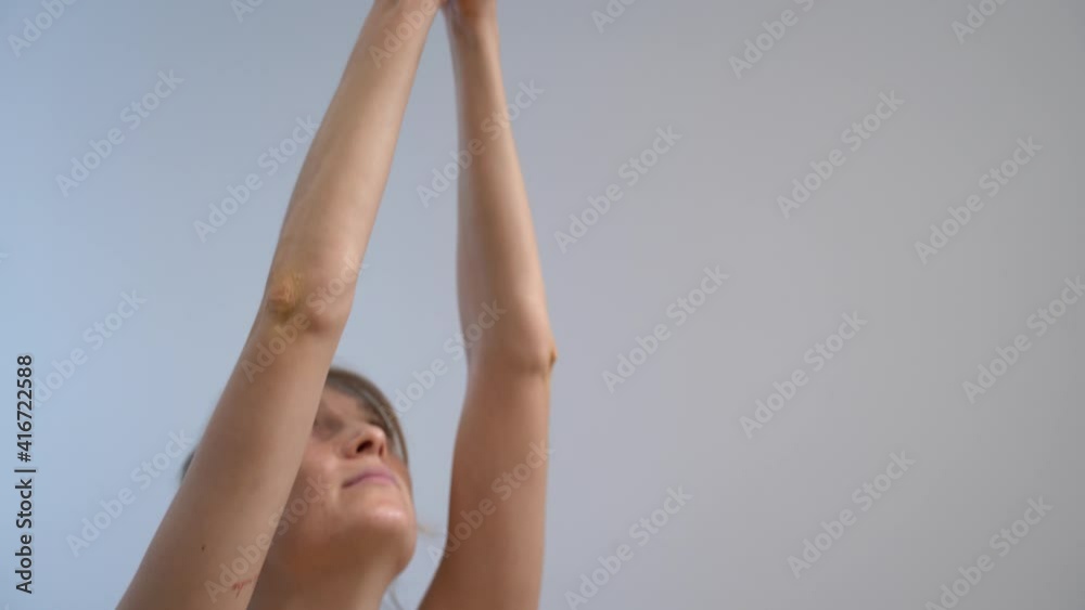 Mujer joven practicando Yoga  en posición de Loto subiendo los brazos y las manos. Plano cerrado