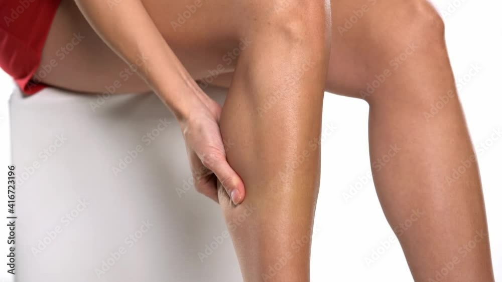 a young woman massaging the muscles of her lower leg on a white background a young woman massaging the muscles of her lower leg on a white background