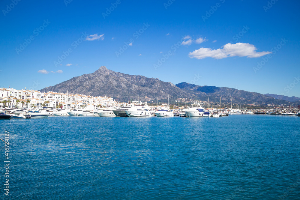 View of Puerto Banus marina with boats and white houses in Marbella town at sunrise, Andalusia, Spain