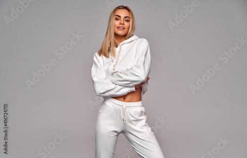 Beautiful sexy blonde woman wear of white set of tracksuit isolated on gray background © kiuikson