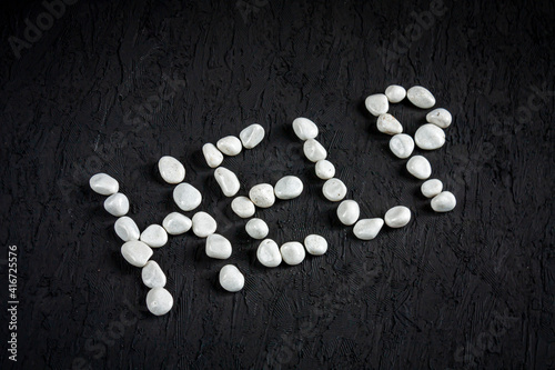 small white pebbles forming a word "help" on black background