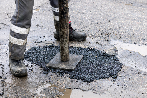 worker pushing bitumen in the hole. road repair and maintenance photo