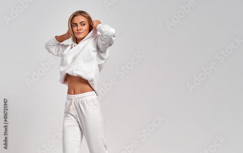 Beautiful blonde woman in white tracksuit isolated on gray background photo