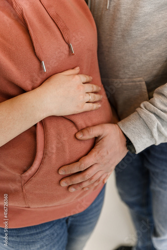 pregnant girl hugs her belly with her hands together with her husband. close-up of a pregnant belly. in anticipation of the child.