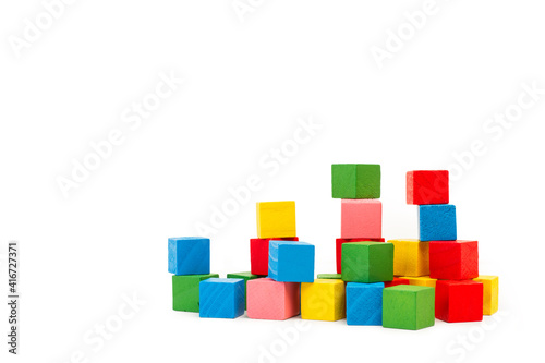 Pila de bloques de madera de diferentes colores sobre un fondo blanco liso y aislado. Vista de frente y de cerca. Copy space
