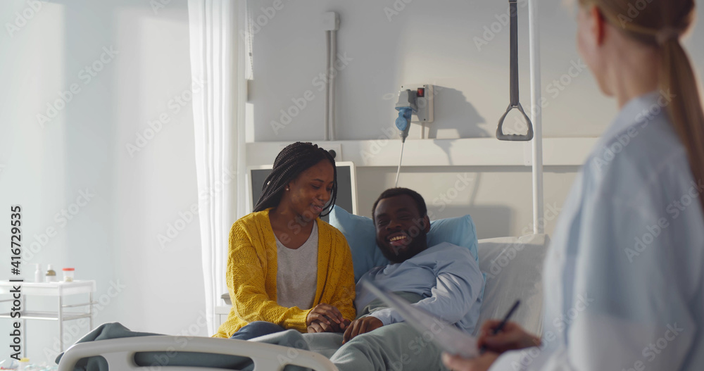 Obraz premium Female doctor talking to african-american couple in hospital room