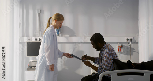 African man patient signing form and being discharged from hospital