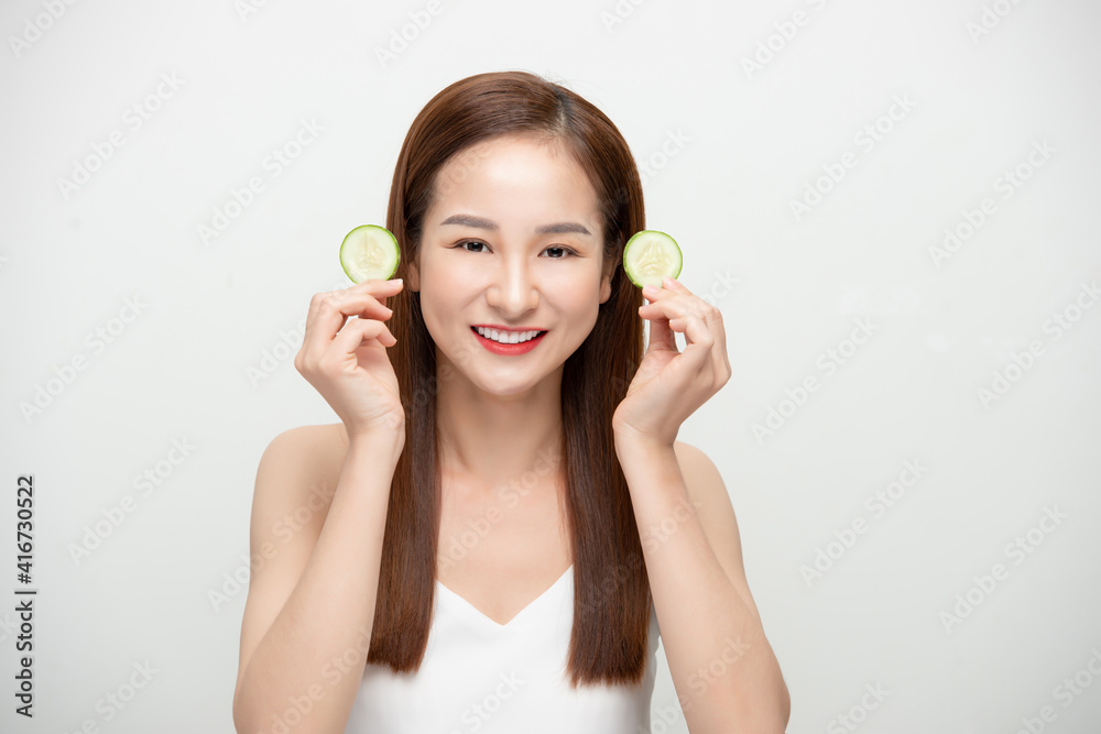 Beautiful joyful Asian woman posing with cucumber and smiling isolated over white background Beautiful joyful Asian woman posing with cucumber and smiling isolated over white background