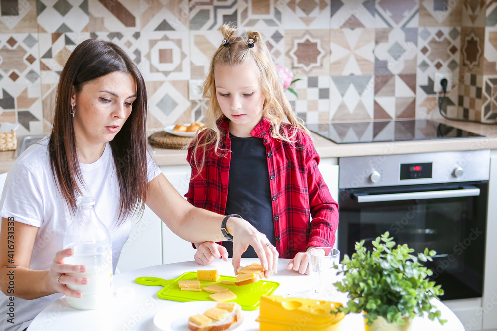 family, food and people concept - happy mother and daughter having breakfast at home family, food and people concept - happy mother and daughter having breakfast at home