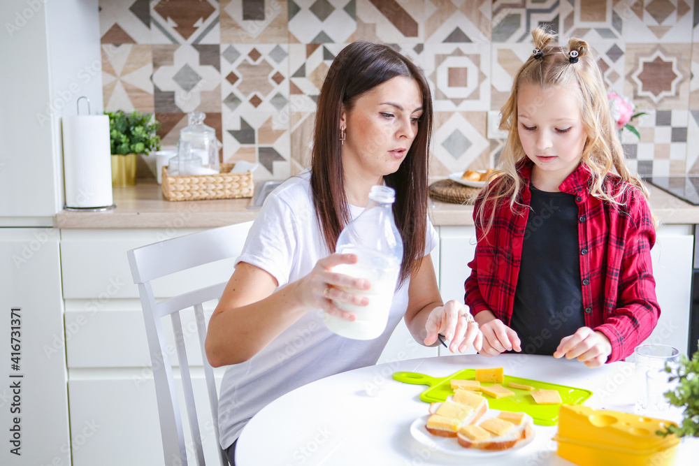 family, food and people concept - happy mother and daughter having breakfast at home family, food and people concept - happy mother and daughter having breakfast at home