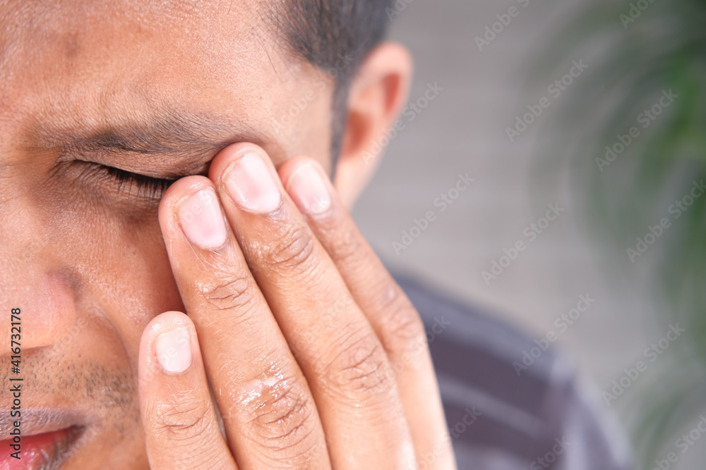 Fototapeta premium Close up of upset man suffering from strong eye pain