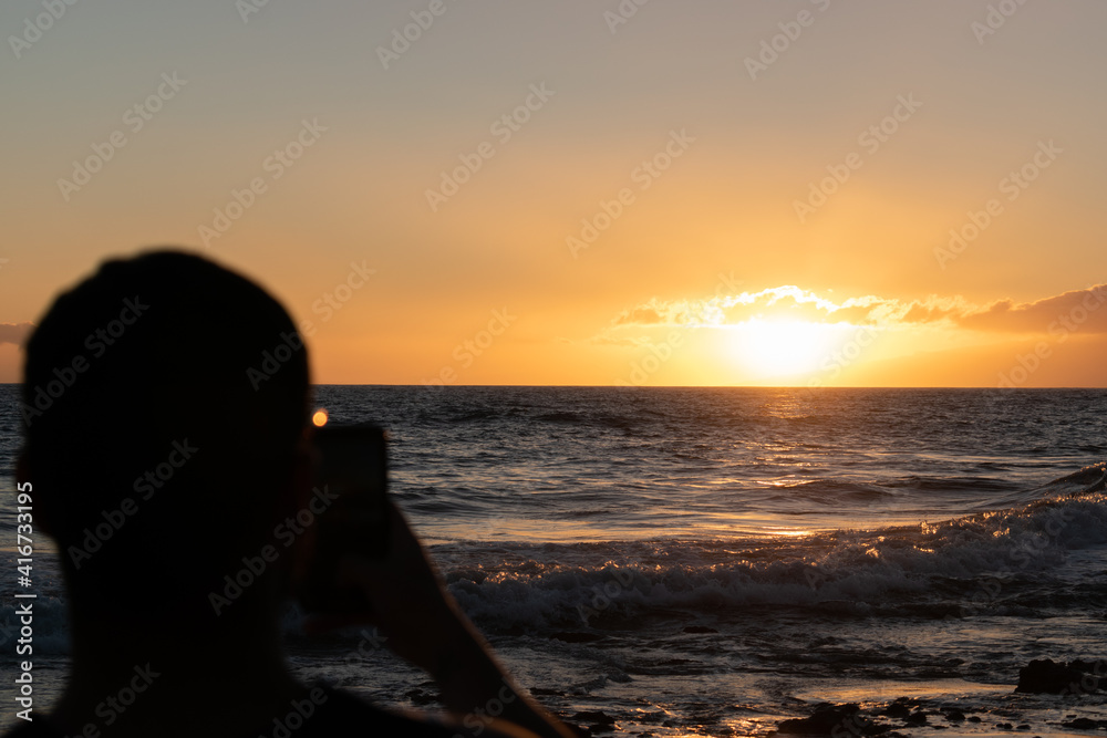 silhouette of young man on the beach taking pictures