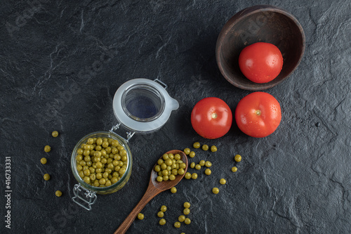 Marinated green olive with tomatoes over black background