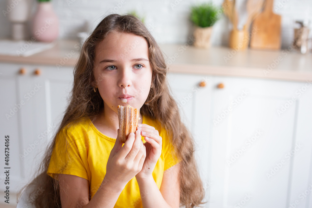 cute school-age girl with curly-haired girls sits at a table in the kitchen, has fun, singing while waiting for food, a delighted child relaxes at the counter, enjoys a happy childhood at home cute school-age girl with curly-haired girls sits at a table in the kitchen, has fun, singing while waiting for food, a delighted child relaxes at the counter, enjoys a happy childhood at home
