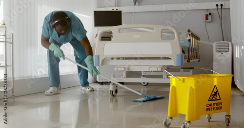 Bild auf Leinwand Afro-american male nurse cleaning patient room in modern hospital