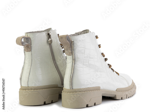 White leather boots with brown laces and zipper on the side. Imitation of crocodile skin. Beige rubber sole. Isolated close-up on white background. Back side view. Fashion shoes. photo