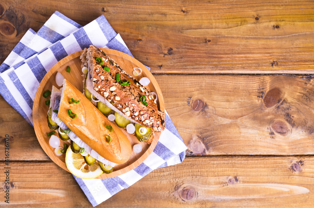 Dutch herring in a sandwich in cereal bread and a white bun. Toast with Dutch herring, onions, pickles. Traditional rustic appetizer with seafood. Popular food in the Netherlands. Copy space Dutch herring in a sandwich in cereal bread and a white bun. Toast with Dutch herring, onions, pickles. Traditional rustic appetizer with seafood. Popular food in the Netherlands. Copy space