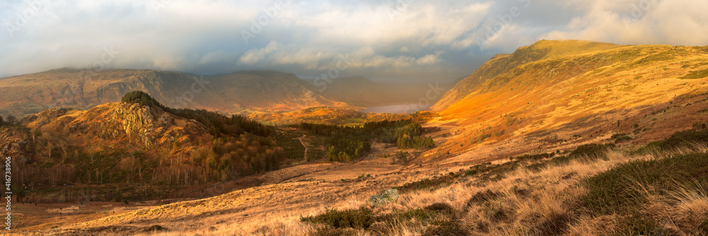 Dramatic panoramic view of Wastwater, surrounded by mountains covered in golden light. Lake District, UK.