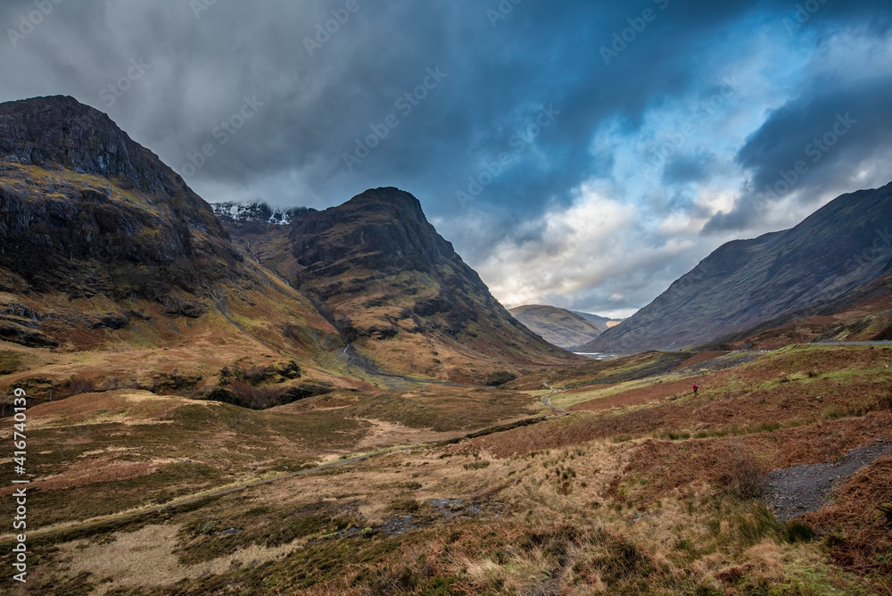 Majestic moody landscape image of Three Sisters in Glencoe in Scottish Highlands on a wet Winter day wit high water running down mountains