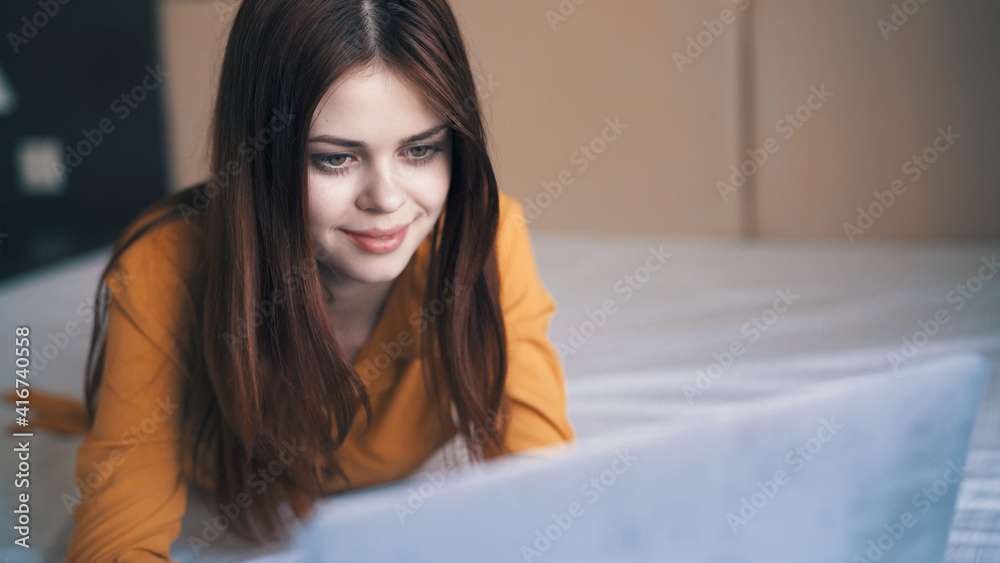 pretty woman lies in front of a laptop in the room work close-up pretty woman lies in front of a laptop in the room work close-up