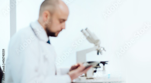 scientist using a digital tablet sitting at a laboratory table.