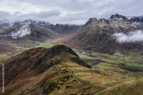 Stunning flying drone landscape image of Langdale pikes and valley in Winter with dramatic low level clouds and mist swirling around © veneratio