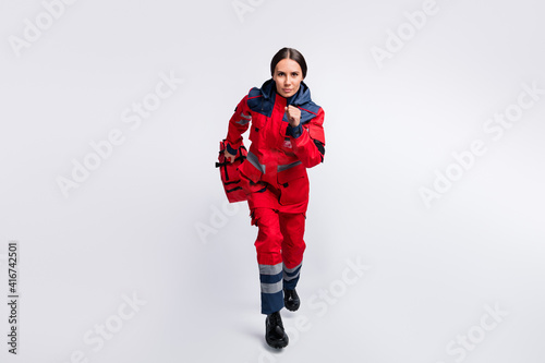 Full length body size view of serious girl skilled doc rescuer jumping running carrying meds isolated over grey pastel color background © deagreez