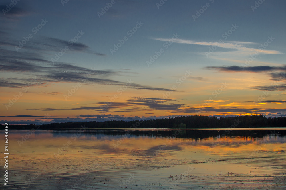 Beautiful sunset landscape over a Finnish lake. The space is flooded with gold.