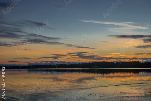 Beautiful sunset landscape over a Finnish lake. The space is flooded with gold.