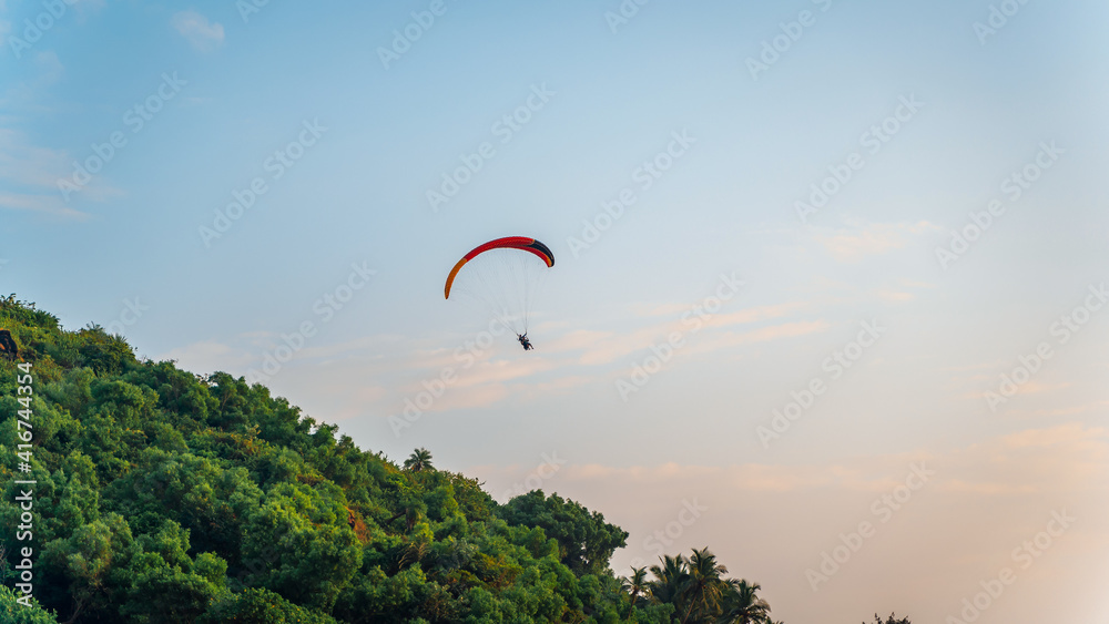A paraglider flying in the blue sky on valleys landscape in India A paraglider flying in the blue sky on valleys landscape in India