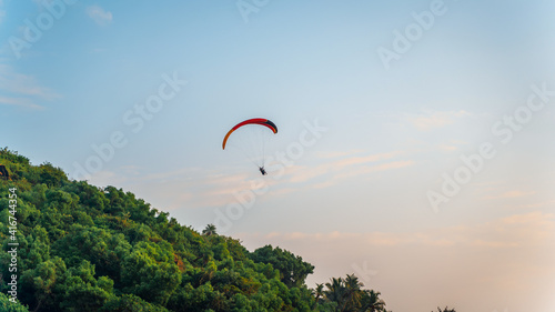 A paraglider flying in the blue sky on valleys landscape in India