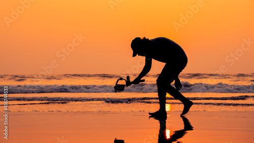 Fotografi A young and independent filmmaker filming near beach silhouette