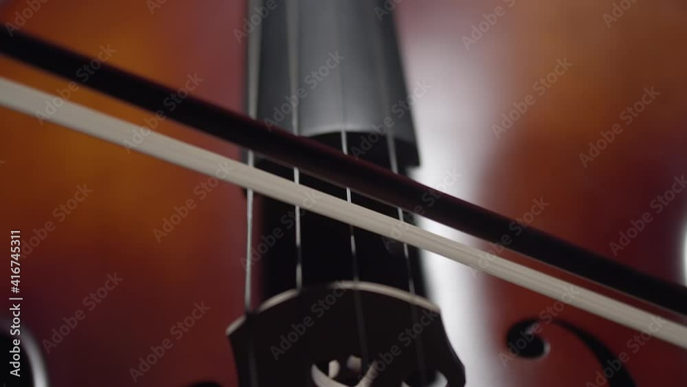 Artist plays with bow on strings of the cello close-up. Musician plays on the cello with hand and bow. Stringed musical instrument Artist plays with bow on strings of the cello close-up. Musician plays on the cello with hand and bow. Stringed musical instrument