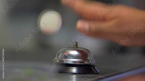 Hand ringing silver counter bell with blurry background