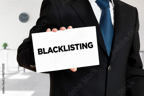 Businessman holds a card with the word blacklisting written on it. s. photo