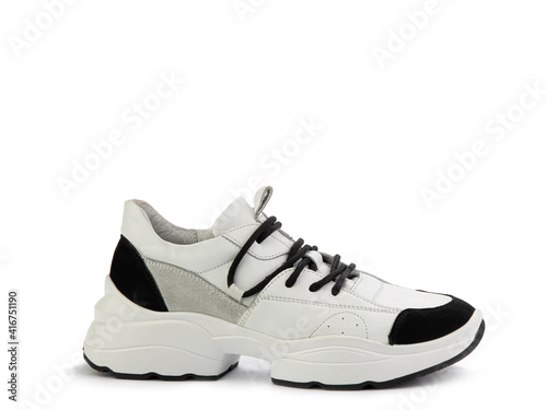 Stylish white women trainers with black and grey suede details. Black lacing and white and black rubber soles. Isolated close-up on white background. Right side view. Casual women's style.