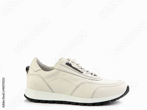Stylish ivory women trainers with white lacing and white and black rubber soles. Isolated close-up on white background. Right side view. Casual women's style.