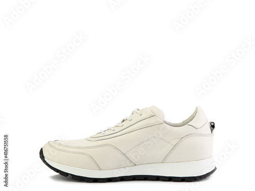 Stylish ivory women trainers with white lacing and white and black rubber soles. Isolated close-up on white background. Left side view. Casual women's style.
