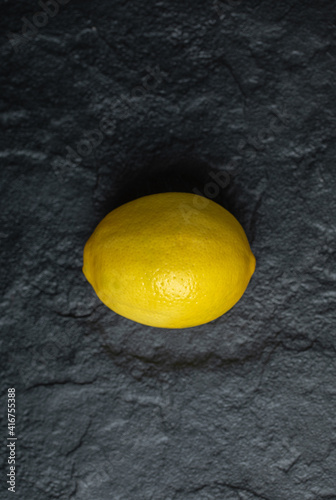 Vertical photo of fresh ripe lemon on the black background