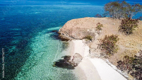 Foto A drone shot of a woman climbing on a big boulder on a paradise island in Komodo National Park, Flores, Indonesia