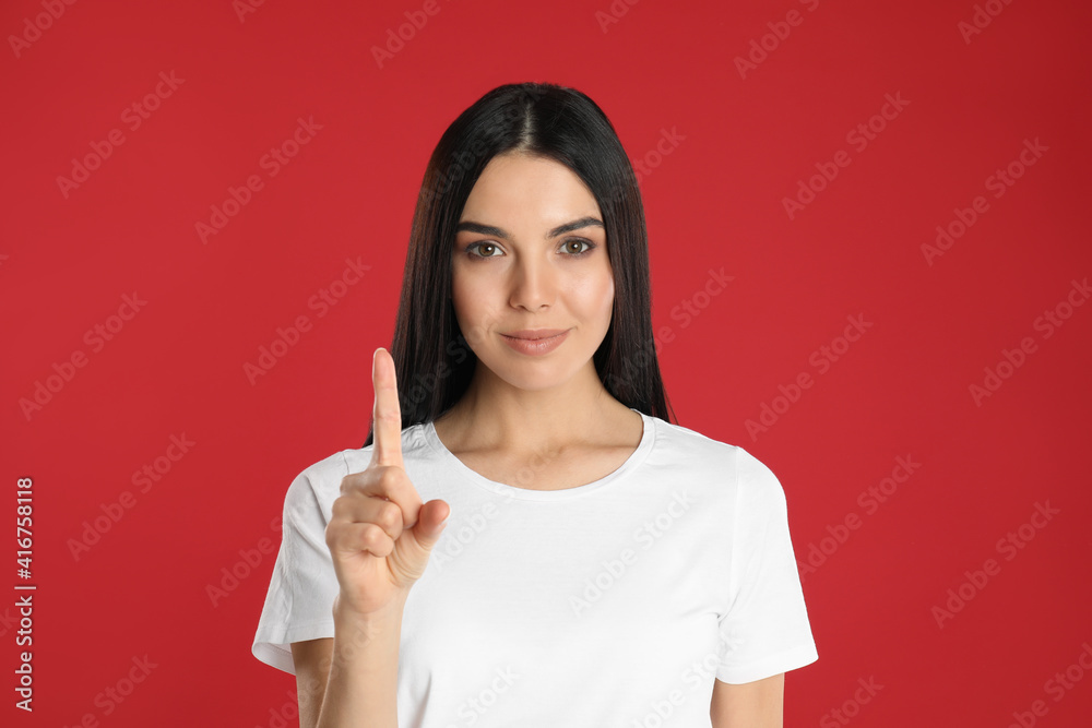Woman showing number one with her hand on red background Woman showing number one with her hand on red background
