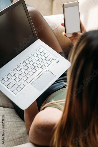 Close up young beautifiul asiatic woman indoors using computer and smartphone photo