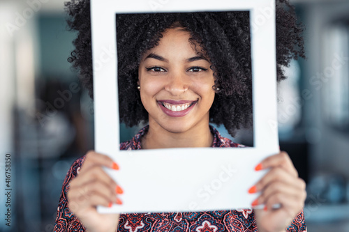 Beautiful afro business woman holding hands frame while posing to camera to snapshot in the office at home.