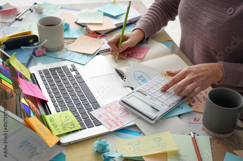 Overwhelmed woman working at messy office desk, closeup photo