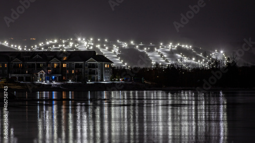 View of Blue Mountain ski resort and village from Lighthouse Point, Collingwood, Ontario. Ski runs are lit up for night skiing for skiers and snowboarders to ski at night during the winter © AshleyBelle