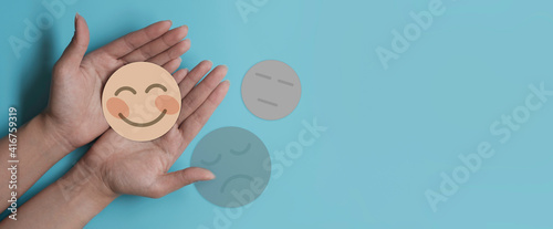 Hand holding blue paper cut happy smile face, positive thinking, mental health assessment , world mental health day concept	