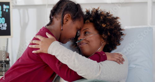 Cute african daughter visiting sick mother in hospital and hugging