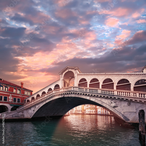 Rialto bridge on The Grand Canal in Venice, Italy in the evening on sunset. Pink purple sky with clouds.Toned square image. Famous place, romantic sights of Venice in Italy.